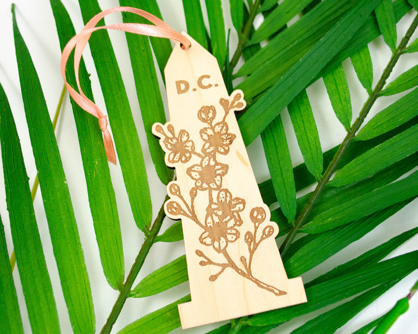 handmade laser cut maple wood ornament of the washington monument with cherry blossoms and the word "D.C." engraved at the top