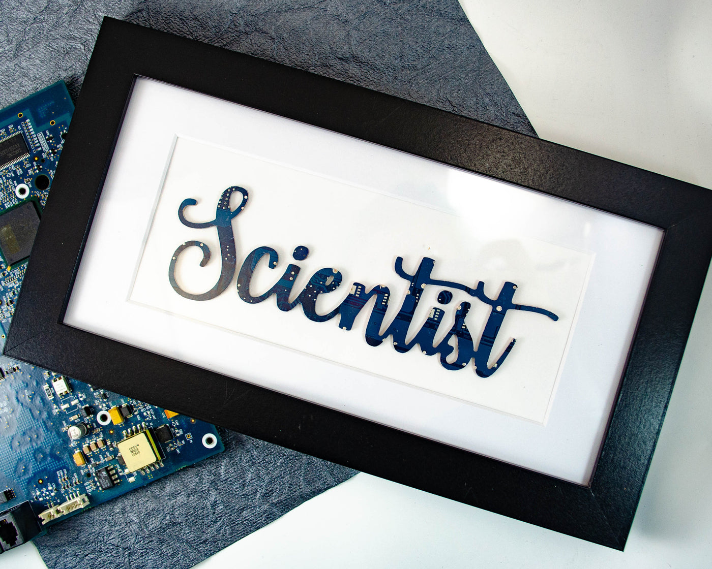 handmade framed art piece with scientist written in a hand lettered style made from recycled circuit board